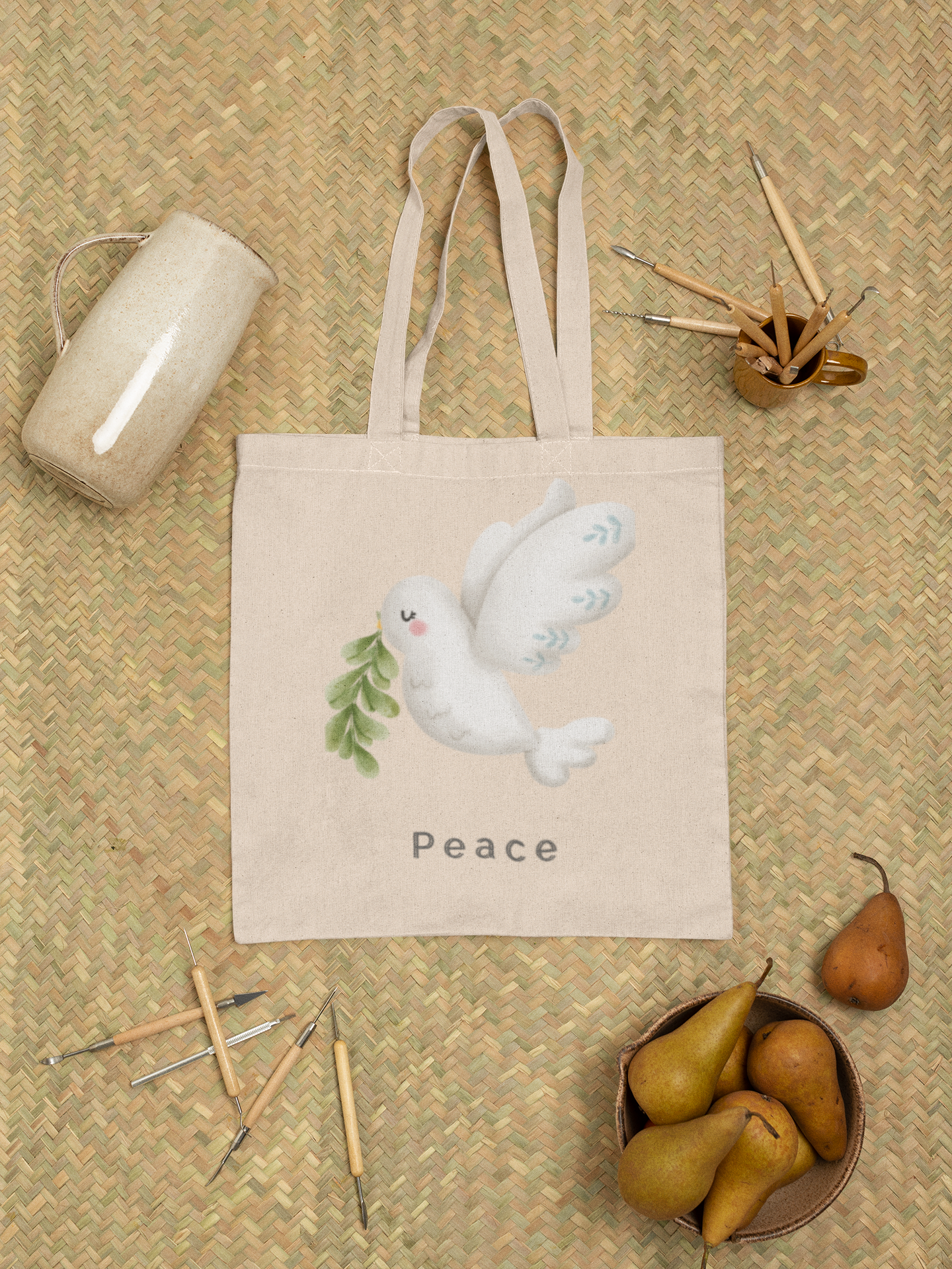 Cream-colored tote bag with a soft watercolor dove carrying olive leaves, above the word “Peace” in minimalist font.